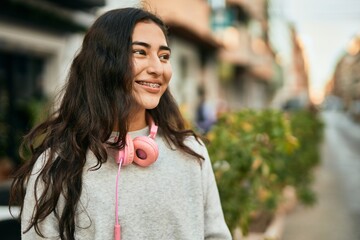 Wall Mural - Young middle east girl smiling happy using headphones at the city.