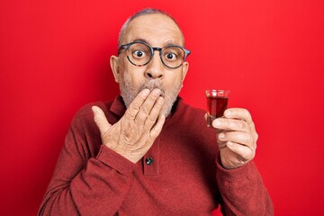 Canvas Print - Handsome mature man drinking whiskey shot covering mouth with hand, shocked and afraid for mistake. surprised expression