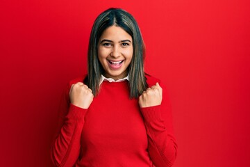 Poster - Young latin woman wearing casual clothes celebrating surprised and amazed for success with arms raised and open eyes. winner concept.