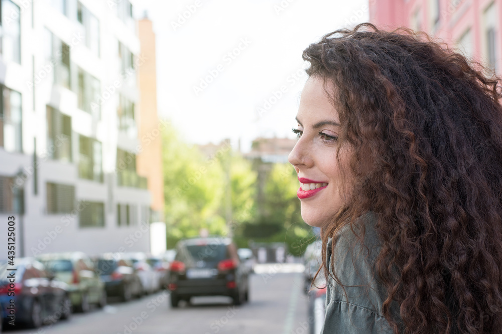Portrait of curly-haired young woman on the street. Latin woman. Arab woman.