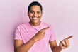 © Krakenimages.com - Young handsome hispanic man wearing casual pink t shirt smiling and looking at the camera pointing with two hands and fingers to the side.