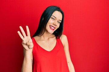 Poster - Young hispanic girl wearing casual style with sleeveless shirt showing and pointing up with fingers number three while smiling confident and happy.