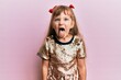 Little caucasian girl kid wearing festive sequins dress sticking tongue out happy with funny expression. emotion concept.