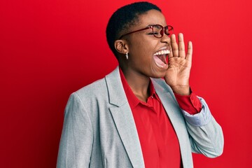 Sticker - Young african american woman wearing business jacket and glasses shouting and screaming loud to side with hand on mouth. communication concept.