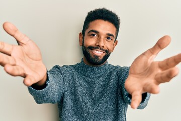 Wall Mural - Handsome hispanic man with beard wearing casual clothes looking at the camera smiling with open arms for hug. cheerful expression embracing happiness.