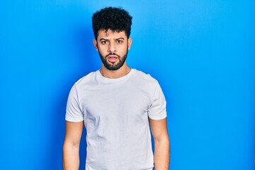 Sticker - Young arab man with beard wearing casual white t shirt in shock face, looking skeptical and sarcastic, surprised with open mouth