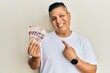 © Krakenimages.com - Young latin man holding 500 mexican pesos banknotes smiling happy pointing with hand and finger