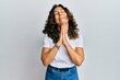 © Krakenimages.com - Middle age hispanic woman wearing casual white t shirt begging and praying with hands together with hope expression on face very emotional and worried. begging.