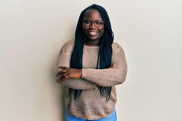 Wall Mural - Young black woman with braids wearing casual clothes and glasses happy face smiling with crossed arms looking at the camera. positive person.