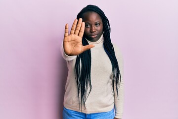 Sticker - Young black woman with braids wearing casual winter sweater doing stop sing with palm of the hand. warning expression with negative and serious gesture on the face.