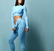 Physical perfection. Sexy sporty fit woman with perfect abdominal muscles on a blue background. Unrecognizable young brunette woman in seductive sporty blue leggings and top. Sport concept.