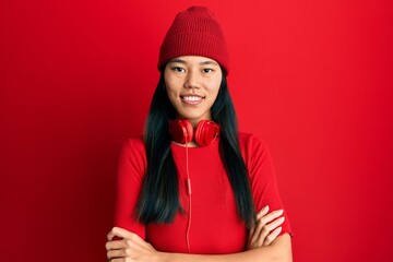 Sticker - Young chinese woman listening to music using headphones happy face smiling with crossed arms looking at the camera. positive person.