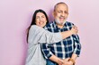 © Krakenimages.com - Young brunette woman and senior man standing over pink background. Daughter and father hugging and bonding together as happy family