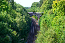 Stone Bridge Over The Railway Surrounded By Green Forest In Scotland, Wales. Romantic Stone Bridge Over Railway In Beautiful Forest, UK. 