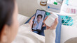 © ChayTee - Over shoulder view of young asia woman talk to doctor on cellphone videocall conference medical app in telehealth telemedicine online service hospital quarantine social distance at home concept.