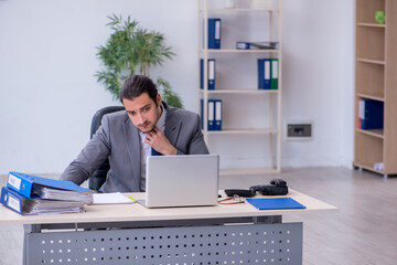 Young male employee unhappy with excessive work in the office