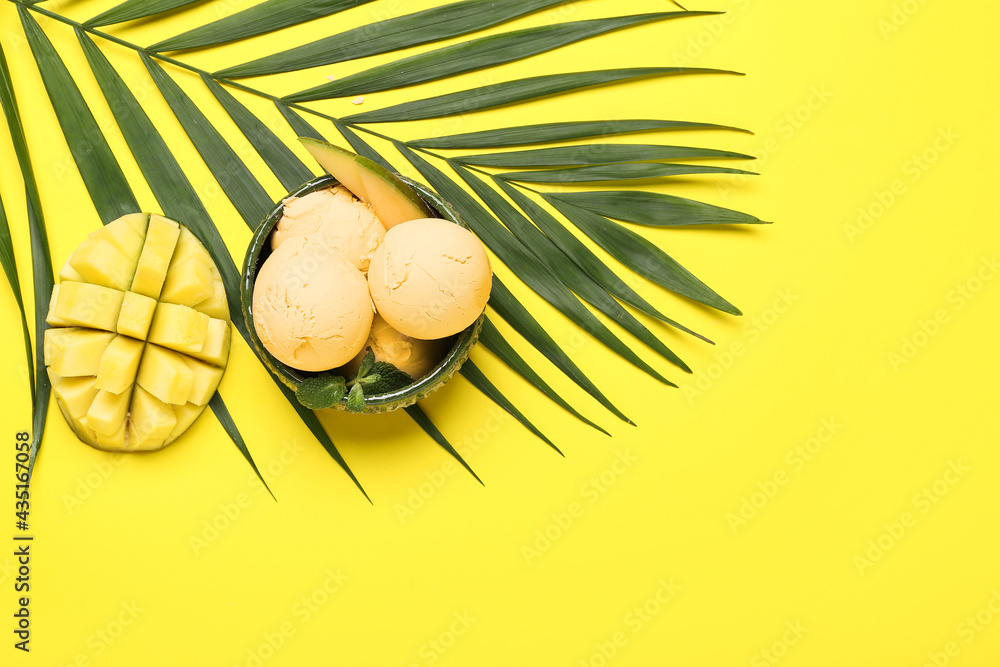 Bowl with tasty mango ice cream and palm leaf on color background