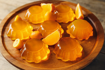 Plate with tasty orange jelly on wooden background, closeup