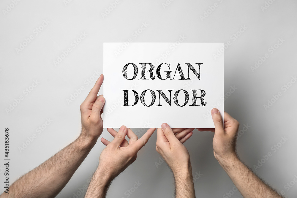 Men holding card with text ORGAN DONOR on light background, closeup - obrazy, fototapety, plakaty 
