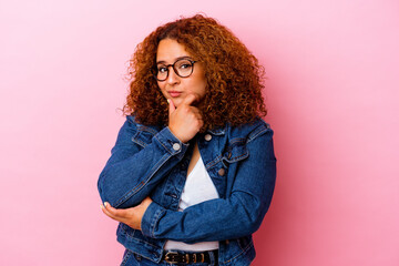 Young latin curvy woman isolated on pink background suspicious, uncertain, examining you.