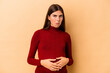 Young caucasian pregnant woman isolated on beige background shrugs shoulders and open eyes confused.