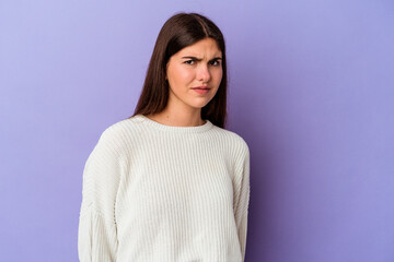 Wall Mural - Young caucasian woman isolated on purple background shrugs shoulders and open eyes confused.