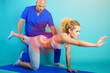 © alphaspirit - Girl performs exercises with a physiotherapist. Cyan background