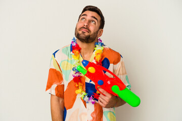 Wall Mural - Young caucasian woman on a hawaiian party holding a water gun isolated on white background dreaming of achieving goals and purposes