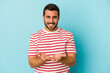 © Asier - Young caucasian man isolated on blue background holding something with palms, offering to camera.