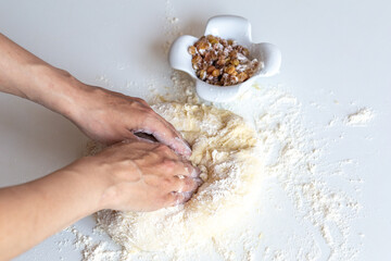 Kneading dough with flour and raisins on a white table close-up