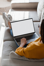 Young Woman Using Laptop Screen Blank, Mockup Lying On Sofa At Home