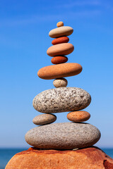 Wall Mural - Rock zen pyramid of colorful pebbles on a background of blue sky