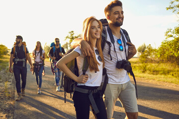 Wall Mural - millennial couple hiking together with their friends in countryside, copy space. happy backpackers t