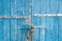 Wooden Background. Old Blue Shabby Wooden Door With Iron Fasteners And A Rusty Lock. Torn Up Dilapidated Boards. Natural Creative Texture For Editing And Design.