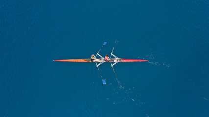 Aerial drone top down photo of sport canoe operated by team of young women in emerald calm sea waters