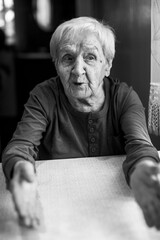 Wall Mural - An old woman talks by gesturing her hands. Black and white portrait.