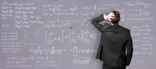 Self-education concept with back view on man in black suit in front of college blackboard with mathematical eqations.