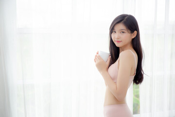 Wall Mural - Beautiful young asian sexy woman in underwear drinking coffee near windows in the morning, girl with seductive figure fit drinking beverage for relax and resting after wake up, lifestyle concept.