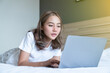 © T-REX - Asian woman lying down and smiling the bed and laptop