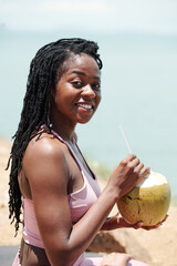 Wall Mural - Portrait of pretty young woman drinking coconut cocktail after training on beach