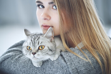 Wall Mural - Beautiful young woman with a cute cat is resting at home. High quality photo.