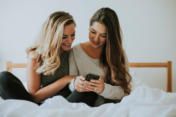 Wall Mural - Girls playing with a phone in bed