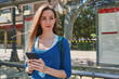 © a2gover - Girl smiling and using mobile while waiting at bus stop