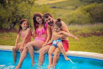 Wall Mural - Happy family sitting by the swimming pool.