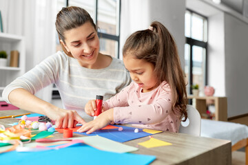 Poster - family, art and craft concept - mother spending time with her little daughter with glue making applique of color paper at home