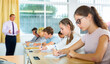 © JackF - Smart teenagers studying in classroom, listening to lecturer and writing in notebooks