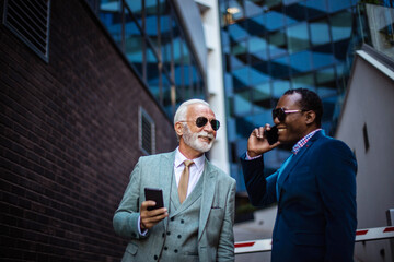 Wall Mural -   Two business men talking on the street. Using smart phones.