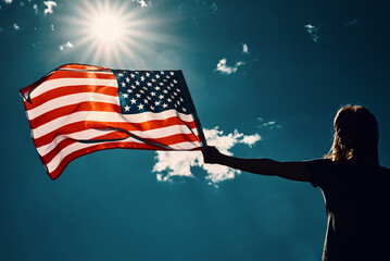 Woman holds usa flag against blue sky