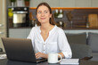 © kucherav - Young caucasian dreamy woman with laptop sitting at table, pensive beautiful female looks to the side trying to present her happy future