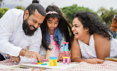 Wall Mural - indian parents having fun at city park playing with wood toys with their daughter - family, summer a